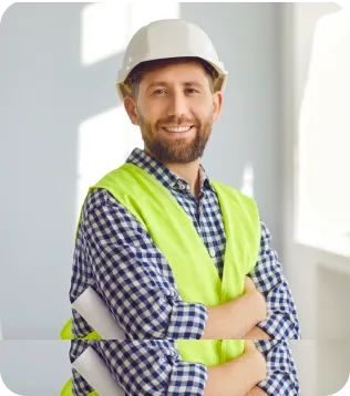 Lächelnder Bauunternehmer mit weißem Helm, Warnweste und Bauplänen unter dem Arm