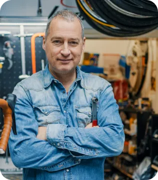 Fahrradmechaniker im Jeanshemd mit Schraubenschlüssel in seiner Fahrradwerkstatt