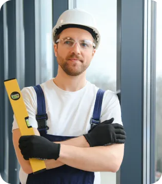 Fensterbauer mit Schutzhelm, Schutzbrille und Wasserwaage bei der Montage eines Fensters