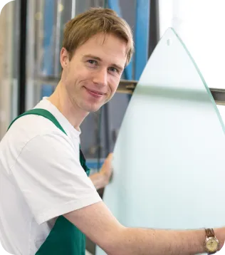 Lächelnder Glaser hält in seiner Werkstatt eine Glasscheibe