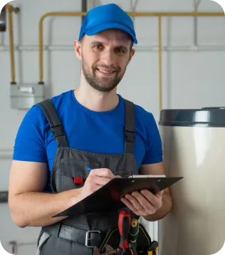 Heizungsbauer in blauer Arbeitskleidung mit Klemmbrett vor einer Heizungsanlage