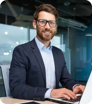 Lächelnder Steuerberater im Anzug arbeitet am Laptop im modernen Büro