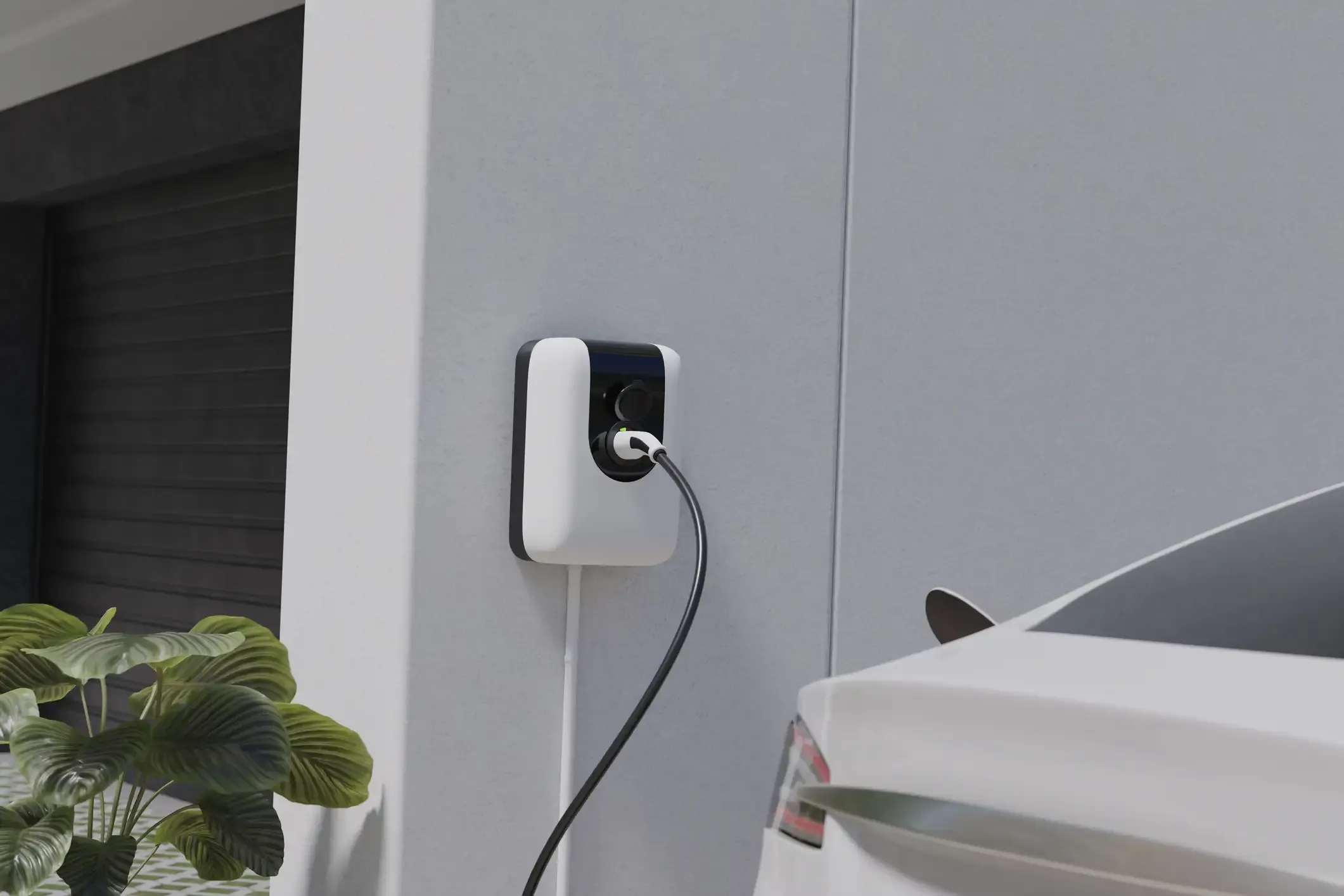 Eine moderne weiße Wallbox an einer Hauswand lädt ein Elektroauto über ein schwarzes Ladekabel auf. Im Hintergrund ist eine Garageneinfahrt zu sehen.