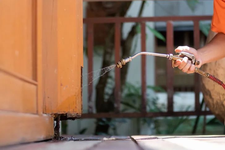 Holzschutz-Anwendung mit Sprühlanze an einem beschädigten Holzpfosten im Außenbereich zum Schutz vor Feuchtigkeit und Schädlingen.